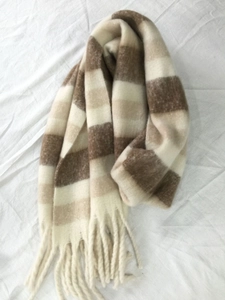 Detail shot of winter scarf tassels with brown and beige striped plaid patterns