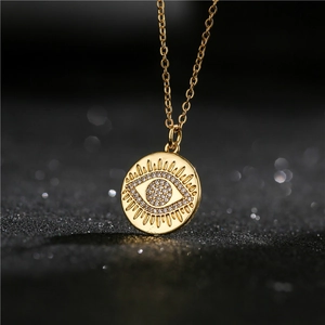 Gold plated evil eye pendant necklace with cubic zirconia on black textured background