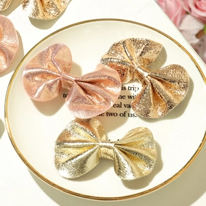 Three-piece metallic bow hair clips in rose gold and light gold on a white ceramic plate
