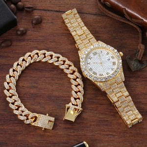 Close-up of gold iced-out watch and Cuban link bracelet set on a vintage wooden desk