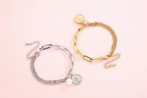 Detail of vintage gold and silver queen coin bracelets with pearls on pink background