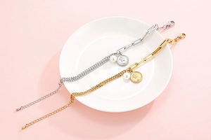 Detail view of gold and silver coin bracelets with pearls on a white porcelain plate