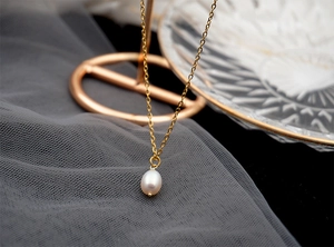 Close-up of a white teardrop freshwater pearl on a delicate gold link chain