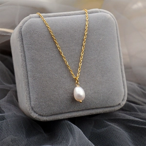 Minimalist gold chain necklace with teardrop freshwater pearl pendant on grey velvet box