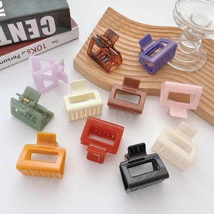 Set of 10 medium square hair claws in various translucent colors on a clean white desk