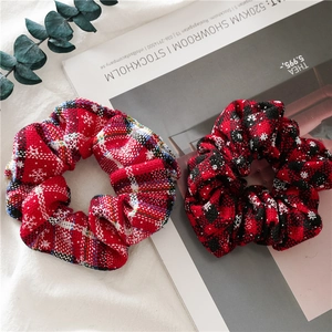 Detail of red and blue snowflake plaid scrunchies on a magazine with eucalyptus leaves