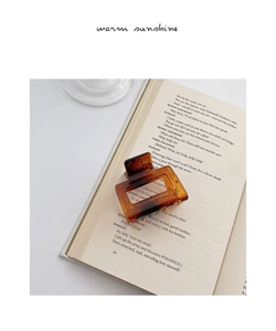 Brown tortoiseshell medium hair claw clip placed on an open book for a vintage aesthetic