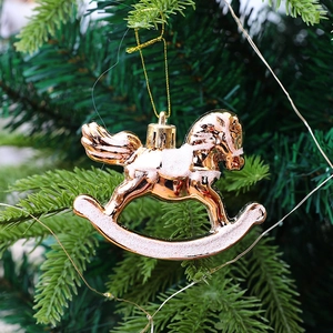 Rose gold Christmas rocking horse ornament with pink glitter on a green tree branch