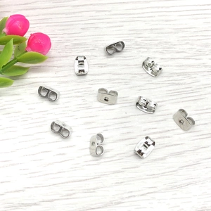 Macro shot of silver stainless steel butterfly earring backs on wooden background