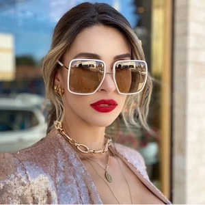 Close-up of white square frame sunglasses with brown gradient lenses on a female model