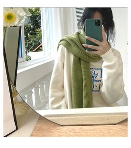 Mirror selfie showing a thick green knitted scarf paired with a cream-white hoodie