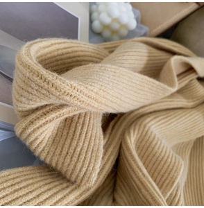 Close-up of beige chunky ribbed knit scarf showing soft texture and thick yarn quality