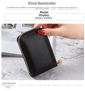 Detail of a black pebbled leather mini card holder with gold zipper on marble background