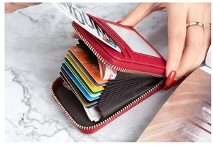 Detailed view of red leather accordion card holder with multiple slots and zipper closure