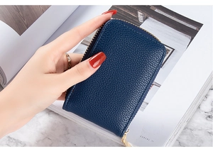 Detail of navy blue lychee grain leather card holder with gold zipper and pebble texture