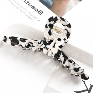 Close-up of a large black and white marble acetate hair claw clip with golden metal spring