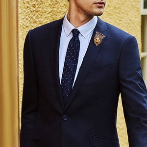 Detail of golden lion head brooch with crown on navy suit lapel for men's formal wear