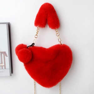 Detail of red heart-shaped faux fur handbag with gold chain strap and plush ball charm