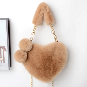 Detail of heart-shaped faux fur bag in camel with plush balls and gold chain strap