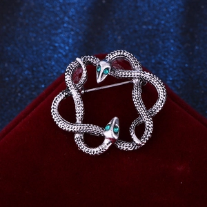 Macro view of vintage silver snake brooch with green rhinestone eyes and scale texture