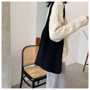 Detalle de un bolso tote de punto negro de gran capacidad combinado con un jersey blanco