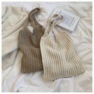 Plano cenital de bolsos tote de punto caqui y crema sobre sábanas blancas suaves