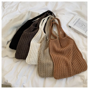 Detalle de seis bolsos tote de punto en tonos tierra sobre una tela blanca