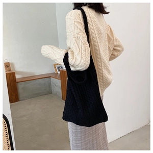 Vista lateral de un bolso tote de punto tejido negro llevado por modelo en estudio