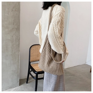 Vista de hombro de un bolso tote de punto beige con textura trenzada gruesa