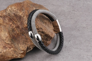 Detail view of double-layer black leather and silver mesh bracelet on natural stone