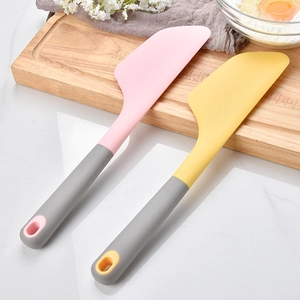 Large pink and yellow silicone spatulas with grey handles on kitchen counter