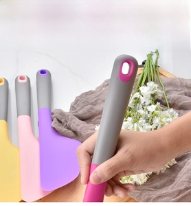 Close-up of colorful silicone baking spatulas with ergonomic hanging hole on wooden tray