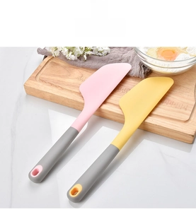 Detail view of pink and yellow silicone spatulas with ergonomic gray handles in a kitchen setting