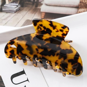 Detail of large tortoise shell hair claw clip with glossy leopard pattern and multi-tooth design