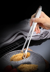 Detailed view of polished 304 stainless steel food tongs holding fried chicken