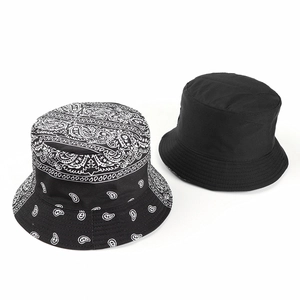 Detail view of double-sided bucket hats in plain black and paisley print patterns