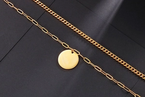 Close-up of gold double-layer chain necklace with cuban links and circular pendant