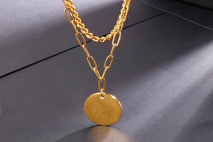 Detail of gold double-layered woven Cuban and paperclip chain with round pendant