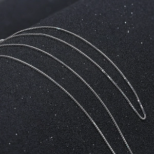 Macro shot of multiple S925 sterling silver box chains on a dark textured surface