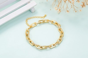Detail of gold paperclip chain bracelet with micro-paved zircons and star accents
