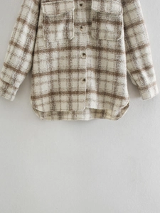 Détail d'une chemise à carreaux marron et beige avec poches à rabat et boutons en résine