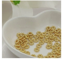 Detailed view of 14K gold plated daisy flower pendants inside a heart ceramic bowl