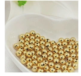 Macro shot of 14K gold plated beads in a white heart bowl for DIY jewelry making
