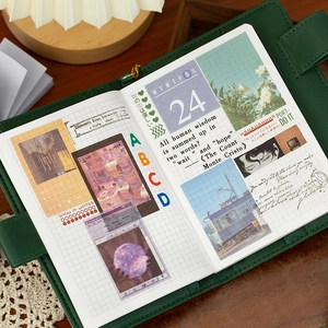 Green vintage notebook with DIY collage stickers and artistic scrapbooking pages on wood