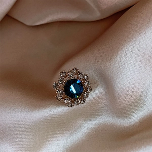 Macro shot of flower brooch with deep blue faceted gem and crystal rhinestones
