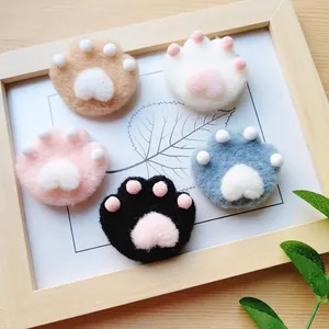Macro shot of five colorful handmade wool felt cat paw brooches in a wooden frame