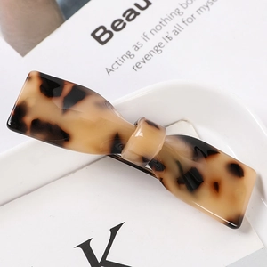 Close-up of tortoise shell bow hair claw clip with golden metal fastener on ceramic tray