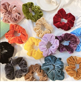 Detailed overhead shot of multi-color velvet scrunchies on white fabric background