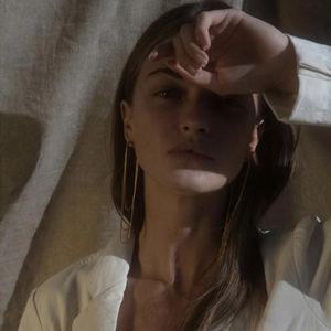 Close-up of minimalist gold U-shaped long tassel earrings on a model in profile