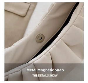 Macro shot of durable metal magnetic clasp on off-white pleated leather handbag